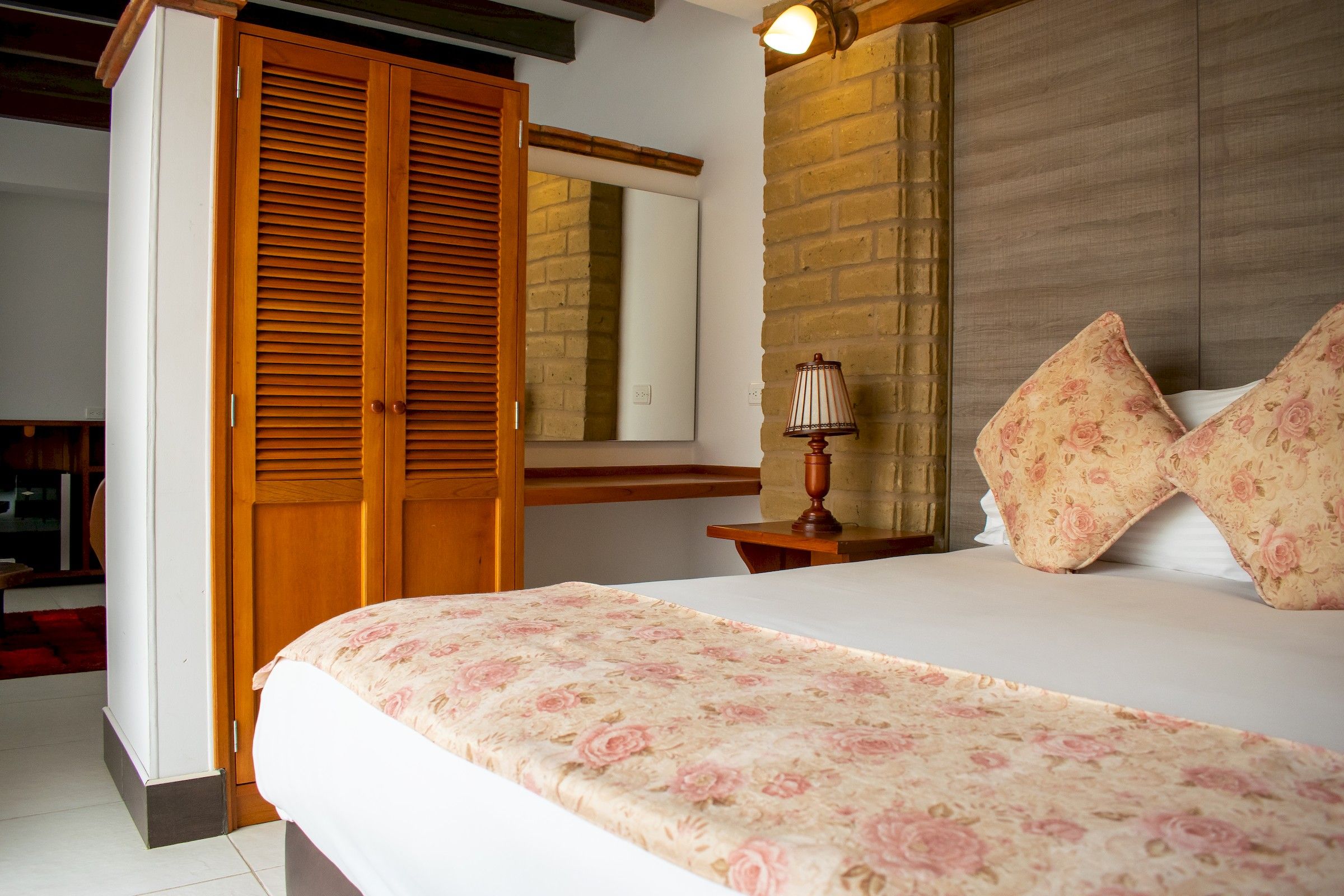 Un dormitorio con una cama, un armario de madera, una mesita de noche, una lámpara y un espejo.