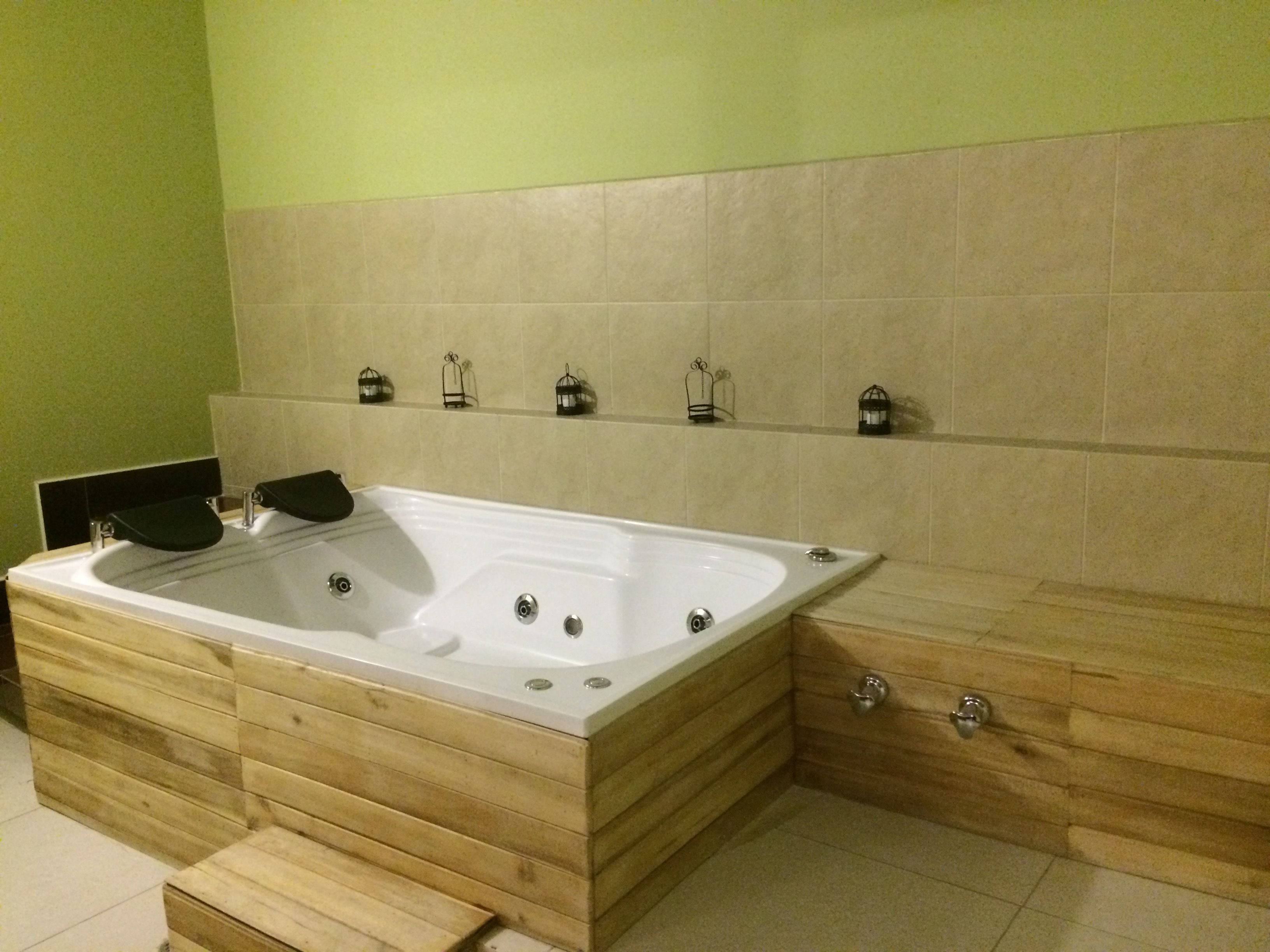Une salle de bain moderne avec une baignoire sur pieds, des meubles en bois et des appliques murales décoratives.