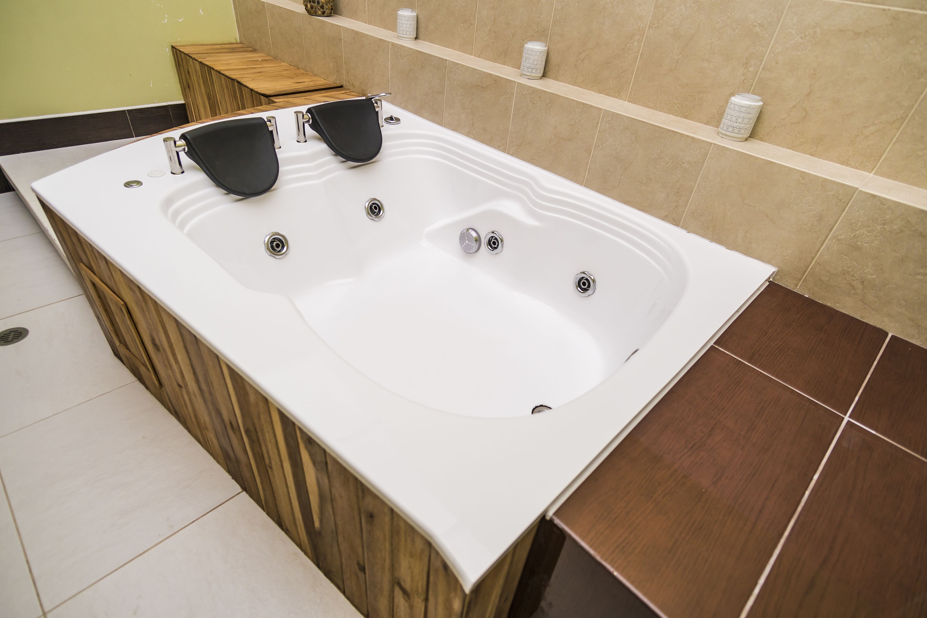 Une salle de bain moderne avec une grande baignoire, des éléments décoratifs en bois et des murs recouverts de carreaux beiges.