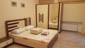 A bedroom with a bed, pillows, a bedside table, a wardrobe, and a radiator.