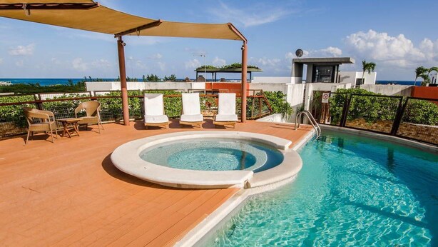 A rooftop pool with a hot tub, lounge chairs, and a view of the ocean. - Heliko 104B by CocoBR (Playa del Carmen)