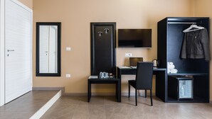 A hotel room with a desk, chair, wardrobe, and a television. - BH Napoli Railway (Naples)