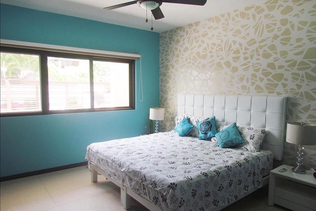 A bedroom with a bed, two bedside tables, a ceiling fan, and a window.