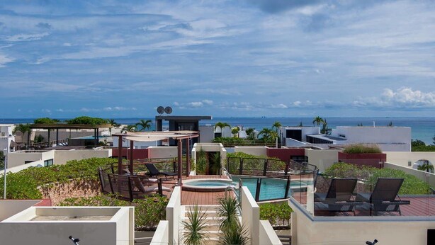 A rooftop pool area with lounge chairs and a hot tub, overlooking a coastal cityscape. - Heliko 102 by CocoBR (Playa del Carmen)