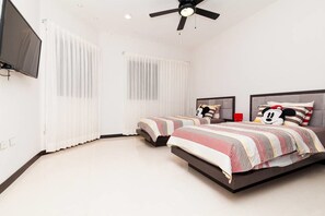 Um quarto moderno com duas camas, um ventilador de teto e uma televisão.