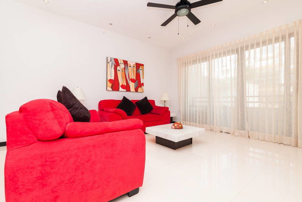 Una sala de estar moderna con un sofá rojo, una mesa de centro blanca y un ventilador de techo.
