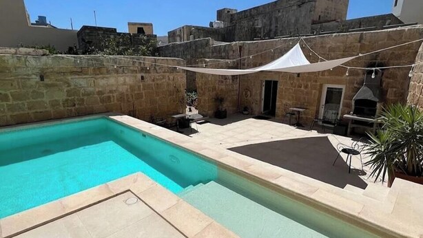 A swimming pool with a stone wall and a white canopy. - Lemon Tree Relais by CX Collection (Zabbar)