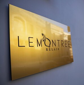 Un letrero dorado con el texto 'LEMONTREE RELAIS' y un diseño de hoja.