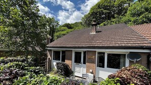 A two-story house with a brick exterior, a tiled roof, and a satellite dish.