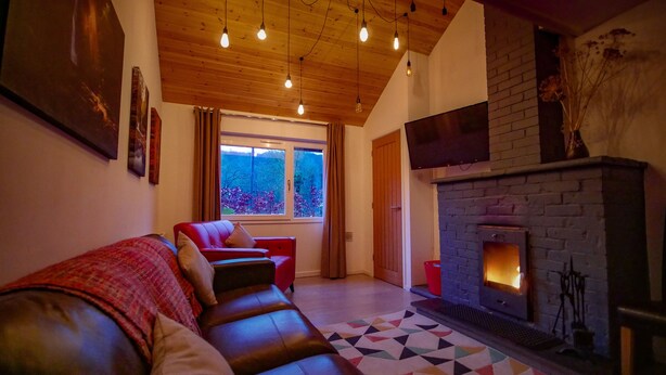 A cozy living room with a fireplace, leather sofa, and a large window.