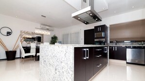 A modern kitchen with a granite island, stainless steel appliances, and a central ventilation hood. - Heliko 201 by cocoBR (Playa del Carmen)