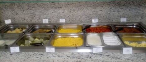 Un bufé con distintos alimentos en recipientes metálicos.