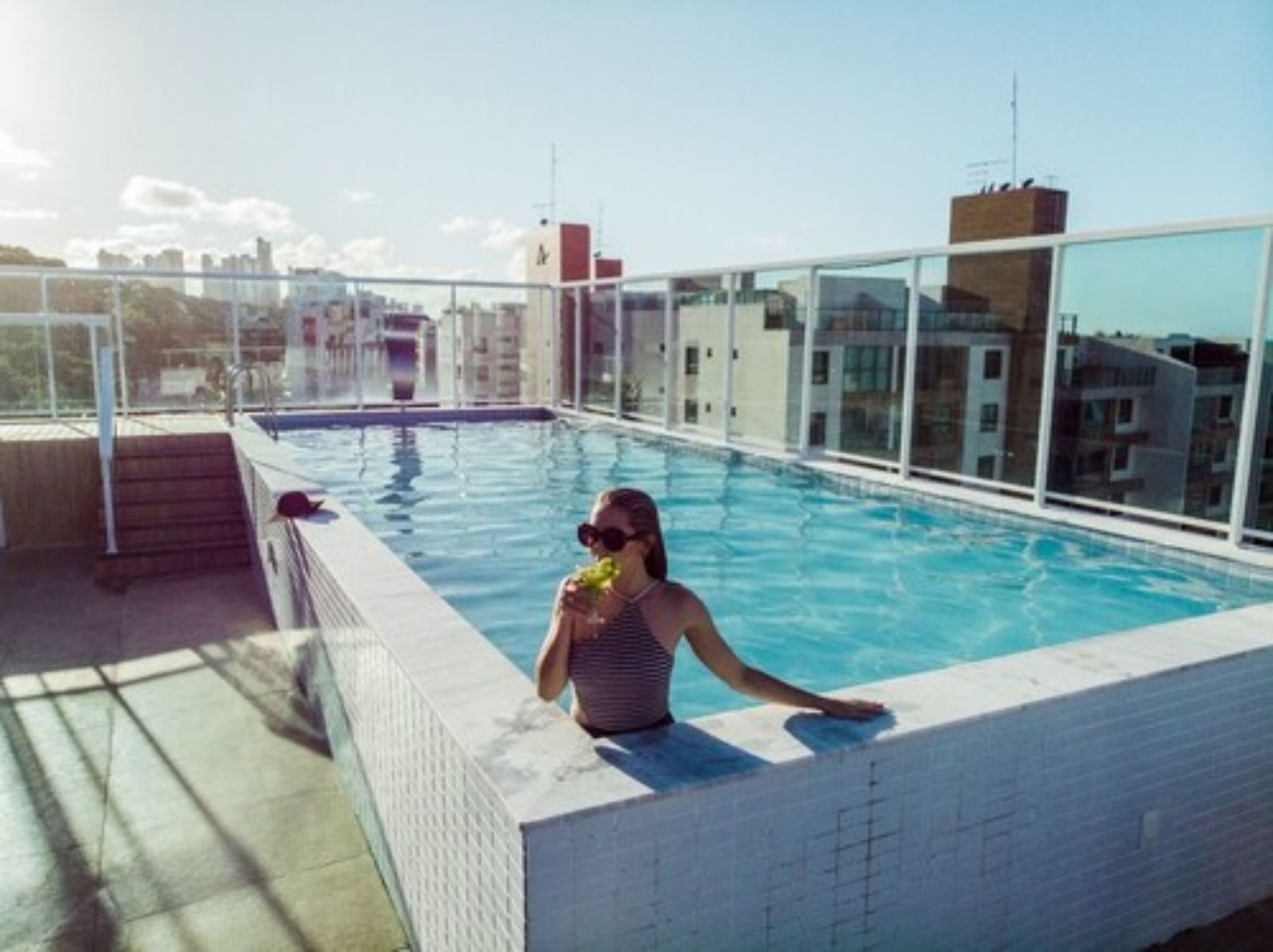 Ein Pool auf dem Dach mit klarem, blauem Wasser, umgeben von Glaswänden mit Blick auf die Stadt.