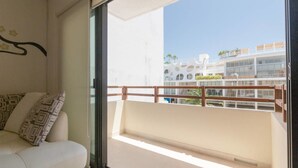 A balcony with a wooden railing, a white sofa with patterned cushions, and a view of a modern building with balconies. - Heliko 305 by CocoBR (Playa del Carmen)