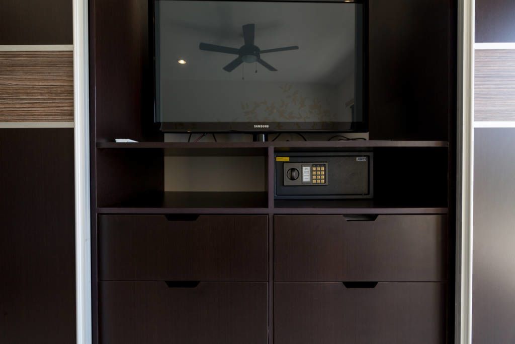 A dark wooden cabinet with a Samsung microwave and a small safe.
