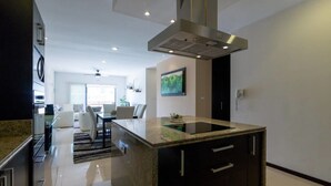 A modern kitchen with a central island, dark cabinetry, and a stainless steel range hood. - Heliko 305 by CocoBR (Playa del Carmen)
