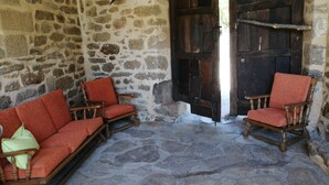 A stone-walled room with two wooden rocking chairs and a red sofa. - La Posada de Pedrazales (Galende)