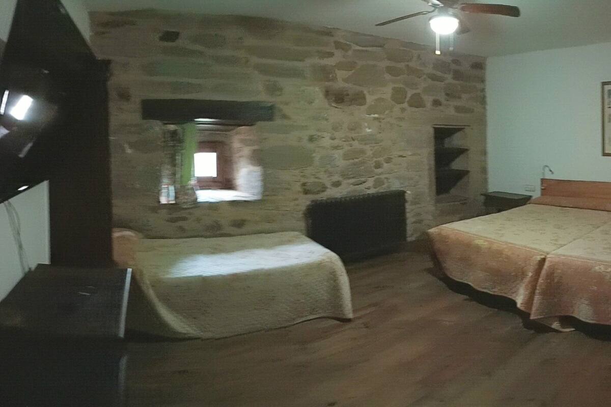 Ein Schlafzimmer mit Steinwand, einem Bett, einem Sessel, einem Fernseher und einem Deckenventilator.