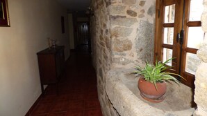 A narrow hallway with stone walls, a wooden door, and a potted plant. - La Posada de Pedrazales (Galende)