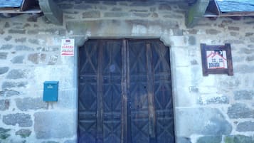 A stone building with a large wooden door and a small signboard.