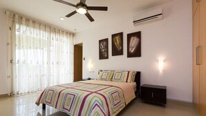 A bedroom with a bed, a ceiling fan, an air conditioner, and three wall-mounted artworks. - Studio one 203 by CocoBR (Playa del Carmen)