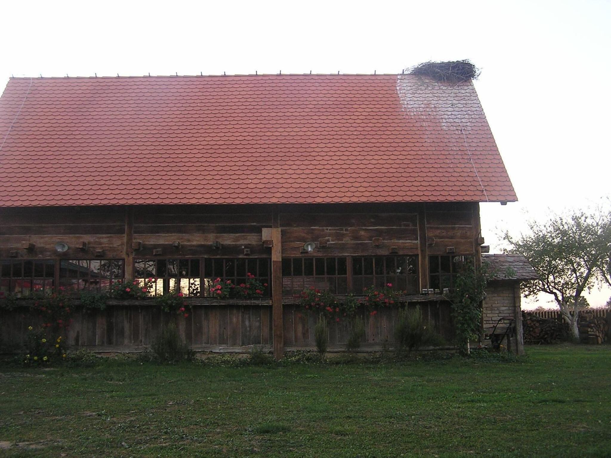 Un edificio de madera con techo de tejas rojas y valla de madera.