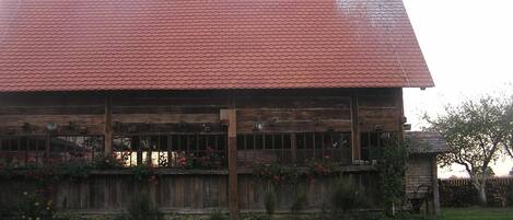 Un edificio de madera con techo de tejas rojas y valla de madera.