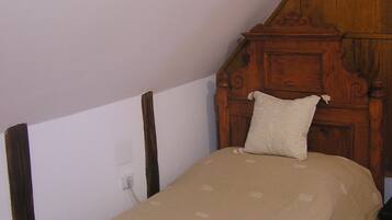 Una cama individual con cabecera de madera en una habitación con techos inclinados.