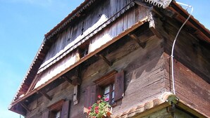 A traditional wooden building with multiple balconies, some with flower boxes. - Tradicije Čigoč (Sisak)