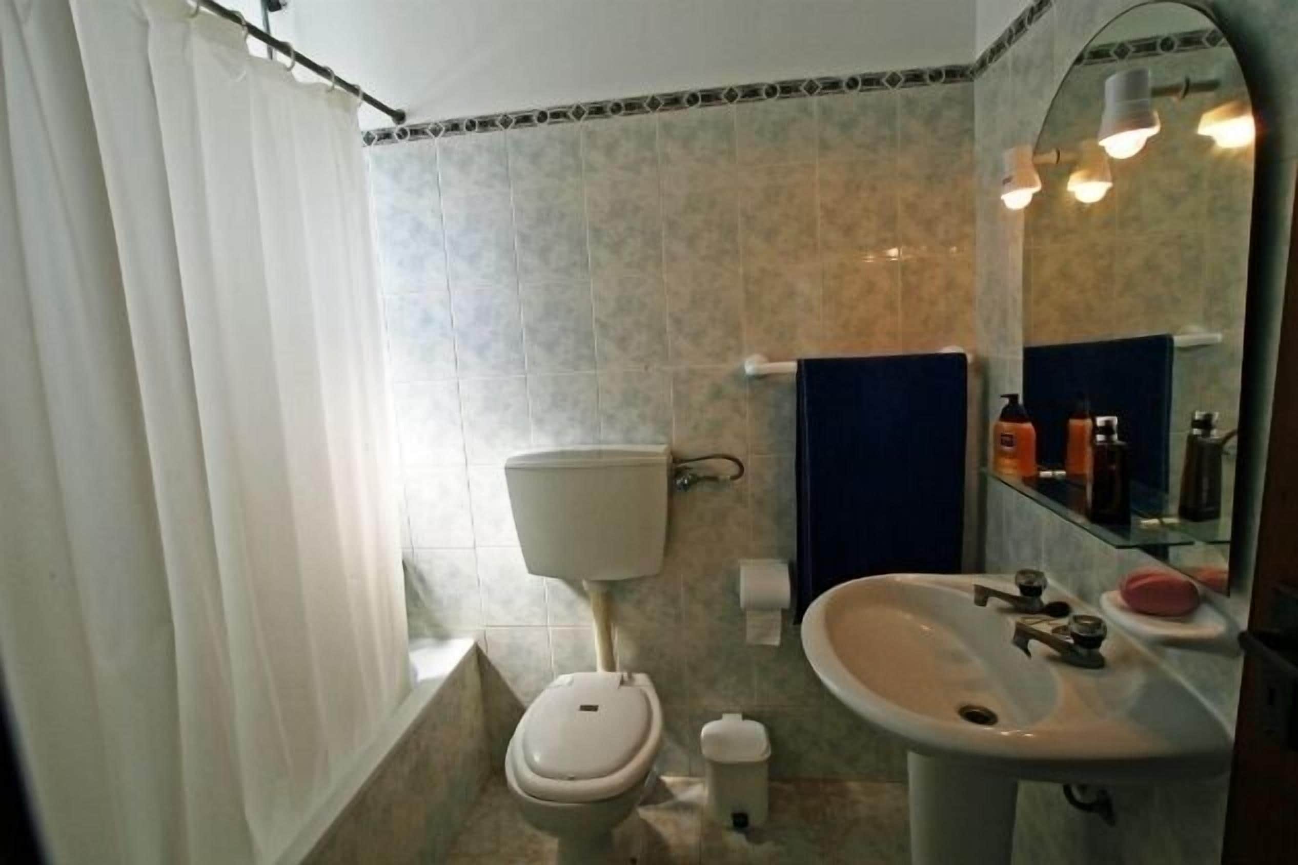 A bathroom with a toilet, sink, and mirror.