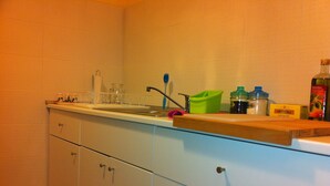 Una cocina con armarios blancos, un lavamanos y varios utensilios de cocina sobre la encimera.