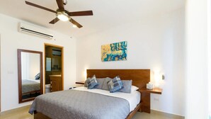 A bedroom with a bed, a ceiling fan, a nightstand, a mirror, and a painting on the wall. - Studio one 208 by CocoBR (Playa del Carmen)
