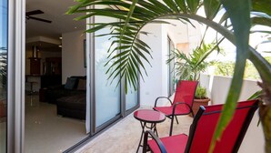 A modern living room with a glass door leading to a balcony. - Studio one 208 by CocoBR (Playa del Carmen)