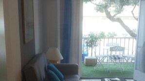 A living room with a sofa, a coffee table, and a view of a balcony with outdoor furniture.