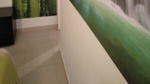 A hallway with a bamboo wallpaper on one wall and a waterfall painting on the adjacent wall.