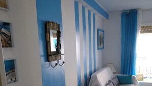 A room with a bed, a chair, a small table, and a window with curtains.