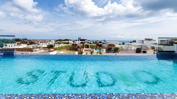 A swimming pool with clear blue water, surrounded by buildings and a view of the sea. - Studio one 303 by CocoBR (Playa del Carmen)