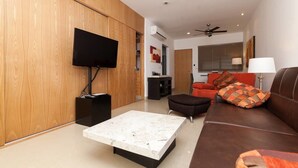 A modern living room with a flat-screen TV, a sofa, a coffee table, and a ceiling fan. - Studio one 303 by CocoBR (Playa del Carmen)