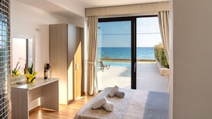 Een moderne slaapkamer met een groot bed, een bureau en uitzicht op de zee door een schuifdeur van glas.