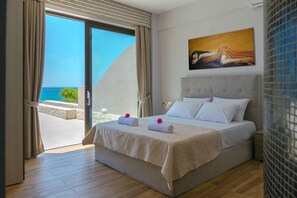 Relax in this serene hotel room with a large bed and sliding glass door leading to an ocean view.