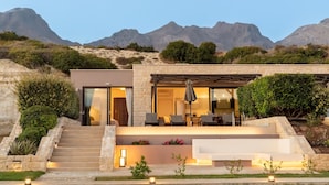 Een modern huis met een gevel van natuursteen, een overdekt terras en een trap naar de ingang.