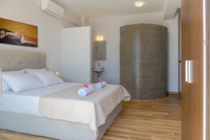 Relax in a serene space with a large bed, modern sink, and a unique textured wall feature.