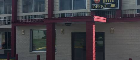 A two-story Budget Inn office building with a red and white exterior, large windows, and a visible entrance.
