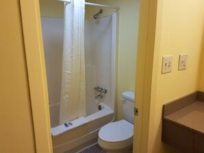 A bathroom with a bathtub, toilet, and a shower curtain. - Budget Inn Tarboro (Tarboro)