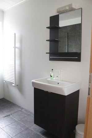 A bathroom with a white sink, black cabinet, and a mirror above it. - Guesthouse Marina Travel (Höfn)