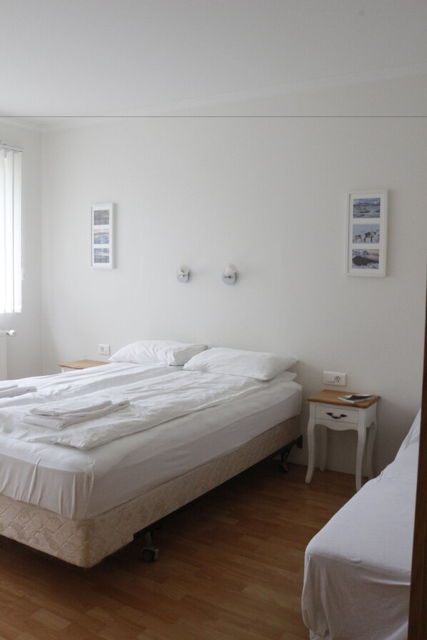 Une chambre à coucher avec un lit simple, une table de chevet, une petite table et un luminaire fixé au mur.