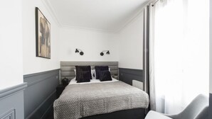 A bedroom with a bed, a chair, a painting on the wall, and two wall-mounted lights. - Black Pearl, 1BR/1BA, 3 people (París)