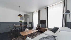 A modern living room with a sofa, a coffee table, and a dining area with chairs and a table. - Black Pearl, 1BR/1BA, 3 people (París)