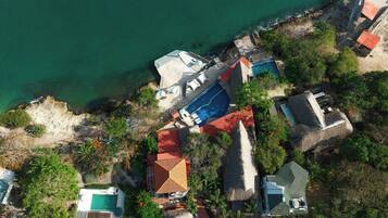 An aerial view of a coastal property with multiple buildings, a swimming pool, and a beach area.