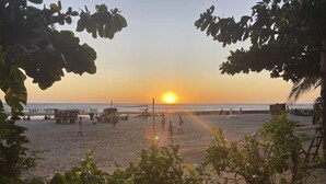 Une plage au coucher du soleil, avec des gens et du matériel de plage.